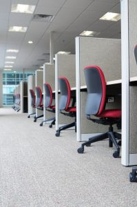 A row of cubicles with red office chairs