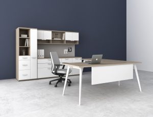 Picture of a modern white office desk in front of white cabinets.